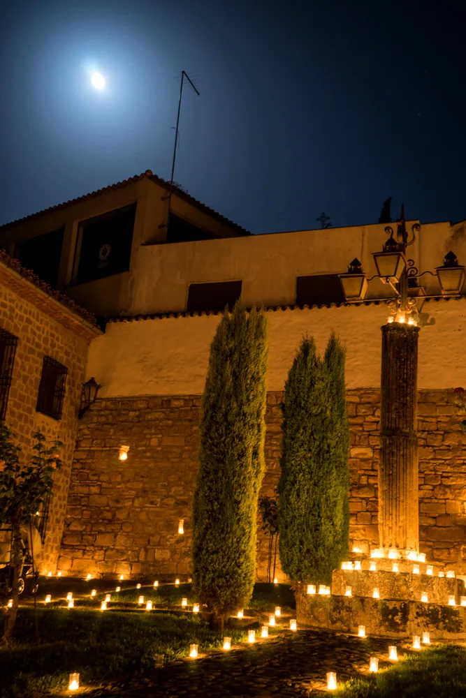 Cipreses junto a la muralla de Baeza iluminados con velas y luna llena